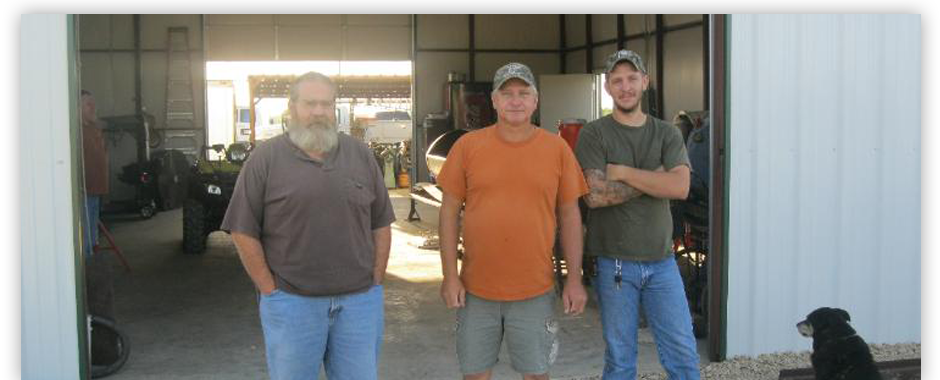 The Page Boiler crew at the workshop — three team members and the shop dog